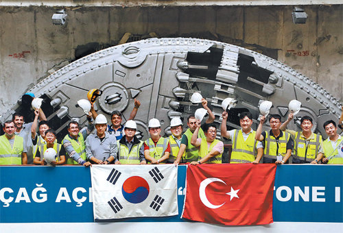 SK건설은 22일 터키 이스탄불에서 유라시아 해저터널 관통 기념식을 열었다. 행사에 참석한 현장 관계자들 뒤로 해저구간 관통 공사에 쓰였던 터널굴착장비(TBM)가 서 있다. SK건설 제공