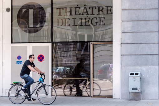 FILE - In this July 31, 2015 file photo, a man rides his bike as he passes the Theatre de Liege, in Liege, Belgium. Japanese designer Kenjiro Sano has refuted claims he copied the emblem of the Belgian theater when he designed the official logo for the 2020 Tokyo Olympics, at a press conference Wednesday, Aug. 5, 2015. (AP Photo/Geert Vanden Wijngaert, File)