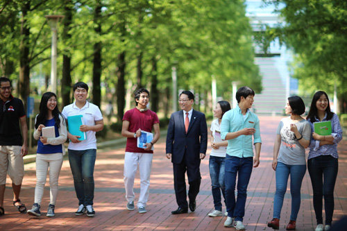 노석균 총장(가운데 양복입은 사람)과 학생들이 캠퍼스를 걸으며 대학생활에 관한 이야기를 나누고 있다.