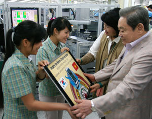 2012년 10월 13일 베트남 박닌 성의 삼성전자 공장에서 이건희 삼성 회장이 현지 직원들로부터 ‘휴대전화 20억 대 누적 생산 기념패’를 받았다.