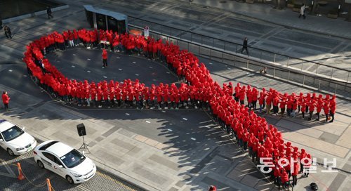 2013년 세계 에이즈의 날을 맞아 한국에이즈퇴치연맹이 서울 청계광장에서 마련한 플래시몹 행사에 참여한 청소년들이 에이즈 퇴치운동의 상징인 빨간 리본을 만들어 보이고 있다. 동아일보DB