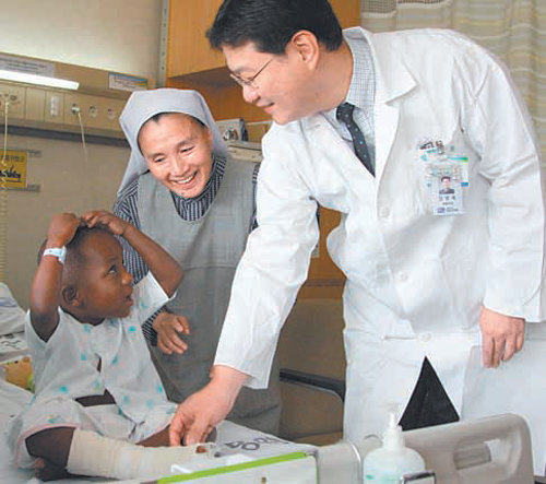 지난달 초 서울성모병원에서 발가락 제거 수술을 받고 회복 중인 선천성 다지합지증 환자 조지프 아린다(9)가 두 팔로 하트 모양을 만들자 김옥단 수녀(가운데)와 임영욱 교수가 환하게 웃고 있다. 서울성모병원 제공