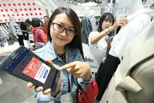 KT가 두타와 함께 중국 관광객을 대상으로 쇼핑 관련 정보를 실시간으로 제공하는 모바일 광고 서비스를 시작했다. 쇼핑몰 앞에서 한국지하철 애플리케이션으로 할인 쿠폰을 확인하고 있는 중국 관광객. 사진제공｜KT