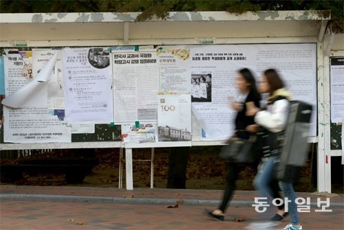 5일 서울 서대문구 이화여대 후문 대자보 게시판 앞을 학생들이 걸어가고 있다. 게시판에는 최근 박근혜 대통령 방문 때 벌어진 학생 시위를 막은 경찰과 학교, 교과서 국정화를 강행하는 정부를 비판하는 대자보 등 여러 장이 붙어 있지만 눈길을 주는 학생은 거의 없었다. 장승윤 기자 tomato99@donga.com