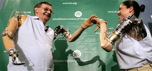 전기화상으로 두 팔을 잃은 미국인 제시 설리반 씨(왼쪽)와 교통사고로 한 팔을 잃은 해병대 출신 클로디아 미첼 씨가 악수를 하고 있다. 이들은 로봇 팔 덕분에 간단한 집안일도 가능해졌다. 인류는 생명공학을 통해 미래에 영생까지 꿈꾸고 있다. 김영사 제공