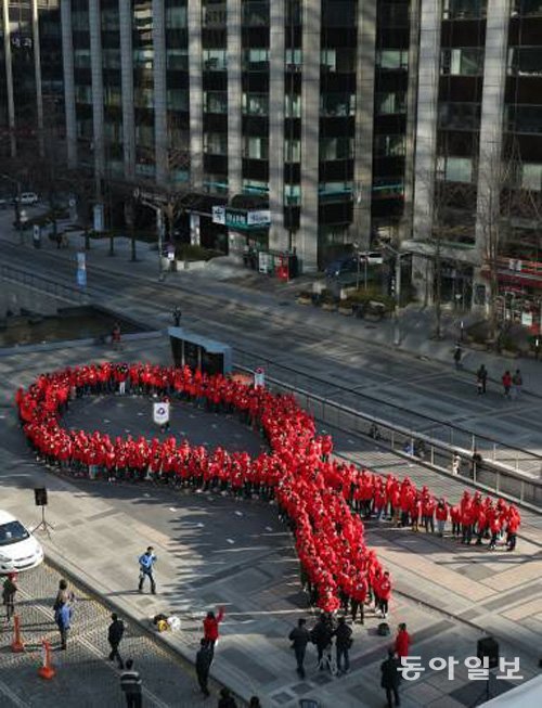 세계 에이즈의 날을 맞아 한국에이즈퇴치연맹이 서울 청계광장에서 마련한 플래시몹 행사. 이 행사에 참여한 청소년들이 에이즈 퇴치운동의 상징인 빨간 리본을 만들어 보이고있다. 동아일보DB