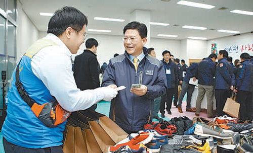 18일 충남 천안시 에스원 인재개발원에서 열린 ‘사랑 나눔 바자회’에서 육현표 에스원 사장(가운데)이 신발을 사고 있다. 에스원 제공