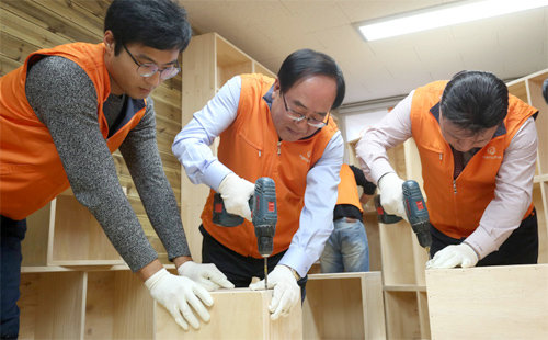 최광호 한화건설 대표이사(가운데)가 23일 서울 구로구 개봉동에서 열린 ‘꿈에그린 도서관’ 개관식에 앞서 도서관에 들어갈 책장을 조립하고 있다. 한화건설 제공