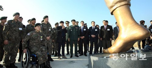 올해 8월 비무장지대(DMZ)에서 북한의 지뢰 도발로 다리를 잃은 하재헌 하사(앞줄 휠체어에 앉은 군인)와 김정원 하사(하 하사 
오른쪽의 두 손을 모은 군인) 등 1사단 수색대대 장병들이 23일 경기 파주시 임진각 평화누리공원에서 열린 ‘평화의 발’ 제막식에
 참석해 조형물을 지켜보고 있다. 조형물 주변에는 실제 DMZ의 흙을 깔아 ‘DMZ를 걷는다’는 의미를 담았다. 파주=양회성 기자
 yohan@donga.com