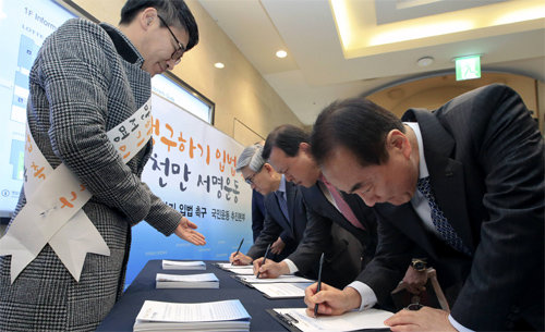 22일 서울 중구 롯데백화점 1층에 설치된 ‘민생 구하기 입법 촉구 서명운동’ 접수대에서 이인원 롯데그룹 부회장(오른쪽) 등 롯데 임원들이 서명을 하고 있다. 롯데그룹 제공