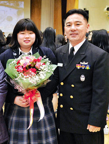 3일 경남 창원시 세화여고에서 열린 졸업식장에 전영규 해군군수사령부 주임원사(오른쪽)가 권은별 양에게 꽃다발을 건넨 뒤 기념촬영을 하고 있다. 해군 제공