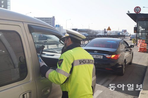 고속도로순찰대 1지구대 김동철 경장이 1일 경부고속도로 부산방향 죽전간이정류장 인근에서 버스전용차로를 주행하다 적발된 승합차 운전자의 운전면허증을 확인하고 있다. 검은색 승용차는 이날 처음 시범 운영을 시작한 경찰의 암행순찰차다. 용인=권오혁 기자 hyuk@donga.com