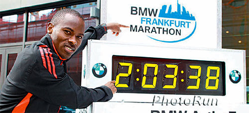 패트릭 마카우(케냐)가 2011년 9월 베를린 마라톤대회에서 2연패에 성공한 뒤 전자시계에 있는 자신의 세계 기록을 가리키고 있다. 구글 이미지 캡처