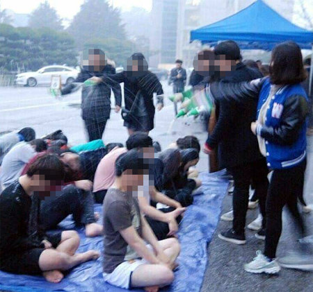 이달 4일 전북 익산시의 한 대학 신입생들이 단과대건물 앞에서 얇은 옷차림으로 바닥에 앉아 선배들이뿌리는 막걸리를 맞고 있다. 출처 페이스북