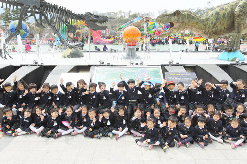 경남 고성공룡세계엑스포 행사장을 찾은 어린이들이 공룡 모형 앞에서 손을 흔들고 있다. 고성군 제공