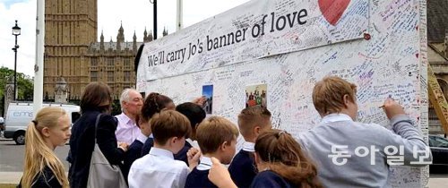 21일 영국 런던 의회광장에 마련된 조 콕스 의원 임시 추모소에는 수많은 시민들의 발길이 이어졌다. 단체로 추모소를 찾은 학생들이
 ‘우리는 콕스 의원의 사랑의 메시지를 이어갈 겁니다’라고 적힌 현수막이 걸려 있는 게시판에 추모 글을 남기고 있다. 런던=전승훈
 특파원 raphy@donga.com