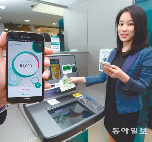 지난해 10월 서울 명동 KEB하나은행 본점에 설치된 현금자동입출금기(ATM)에서 한 직원이 ‘하나멤버스’ 사용법을 설명하는 모습. 동아일보 DB