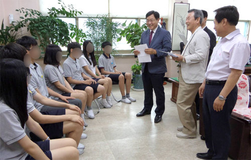 지난달 22일 서울 금천구 난곡중학교에서 난곡휴스턴장학회 김명용 회장(오른쪽 가운데)이 학생 8명에게 장학금이 담긴 봉투를 전달하며 환하게 웃고 있다. 난곡중 제공