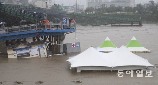 5일 장마전선이 서울, 경기 등 중부지방과 강원지방에 집중호우를 내렸다. 소방대원들이 서울 중랑천 장안교 아래 구조물이 물에 떠내려 가지 않게 하기위해 사투를 벌이고있다. 사진 동아일보