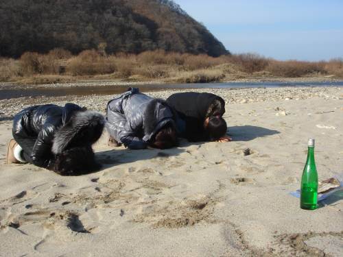 2009년 황강댐 방류 참사에서 남편과 자식을 잃은 유가족 들이 참사 현장인 경기 연천군 임진교 하류 모래섬에서 절을하고 있다.