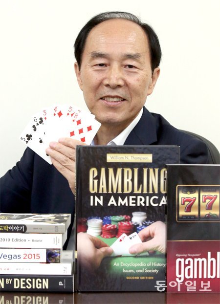 황현탁 한국도박문제관리센터 원장이 카드를 손에 쥐고 세계 각국의 도박 서적이 놓인 책상에 앉았다. 그는 도박을 공부하기 위해 ‘소싸움’을 제외한 모든 게임을 다 경험했다고 말했다. 최혁중 기자 sajinman@donga.com