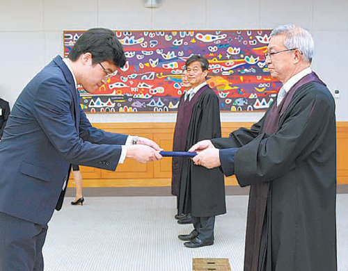 “공정성과 배려를 바탕으로 사회적 약자들의 목소리를 경청하겠습니다.” 1일 신임 법관으로 임명된 윤민욱 판사(왼쪽)가 양승태 대법원장(오른쪽)으로부터 임명장을 받고 있다. 대법원 제공