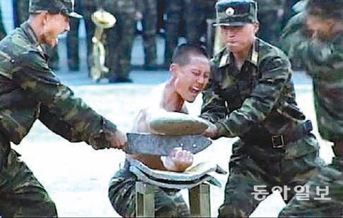 김정일이 지켜보는 가운데 팔뚝에 돌을 올려놓고 망치로 깨부수는 훈련 시범을 보이는 북한 특수부대원. 동아일보DB