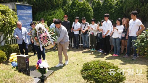 18일 부산 영락공원을 찾은 ‘한일성신학생통신사’ 참가 학생들이 ‘의인 이수현’ 씨의 묘소에 헌화하고 있다. 고인의 아버지 이성대 씨(왼쪽)가 손을 들어 꽃을 놓을 자리를 안내하고 있다. 이 씨 오른쪽은 어머니 신윤찬 씨. 부산=강성명 기자 smkang@donga.com