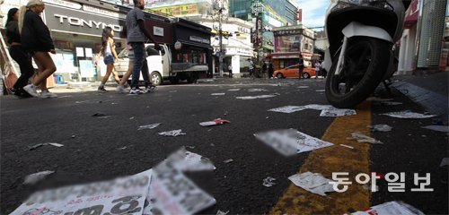 27일 동이 튼 직후 환경미화원들의 손길이 닿기 전 홍대앞거리. 전날 밤 ‘클럽 데이’의 후유증으로 쌓인 홍보 전단과 담배꽁초 등 쓰레기 사이로 외국인 관광객들이 지나가고 있다. 양회성 기자 yohan@donga.com