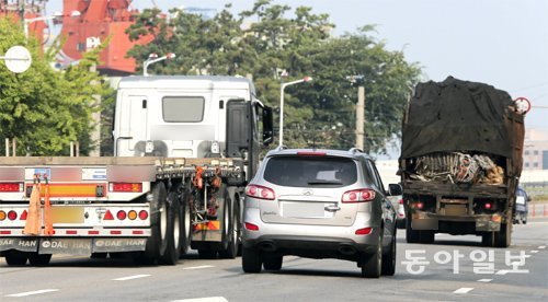 8일 인천항 부근의 한 도로에서 승용차 한 대가 컨테이너 트럭과 짐을 위험하게 실은 화물차 사이를 위태롭게 달리고 있다. 인천=원대연 기자 yeon72@donga.com