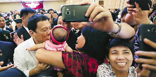 동남아국가연합(아세안) 정상회의 참석을 위해 라오스로 간 로드리고 두테르테 필리핀 대통령이 현지 교민 행사에서 갓난아이에게 입을 맞추며 기뻐하고 있다. 교민들이 두테르테의 모습을 셀카로 앞다퉈 찍고 있다. 사진 출처 마닐라불러틴