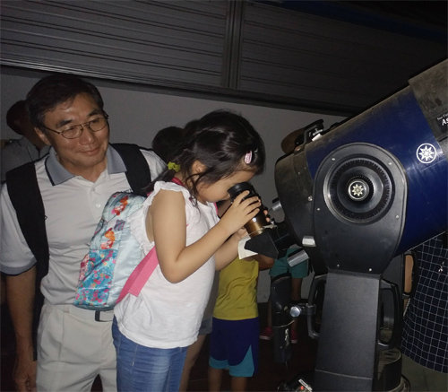 이유신 씨(왼쪽)가 천체망원경으로 직녀성 별자리를 보고 있는 손녀 수민이를 지켜보고 있다. 춘천시내 별과 꿈 관측소 3층 옥상의 관측장.