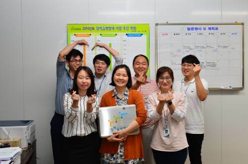 산업인력공단 일학습지원국 일학습확산팀 팀원들이 사무실에서 손으로 하트 표시를 만들어 보이고있다. 뒷줄 왼쪽부터 시계 방향으로 전형식 차장, 노지현 대리, 홍제용 팀장, 지형민 전문위원, 권형정 대리, 문근수 과장, 정혜진 전문위원.