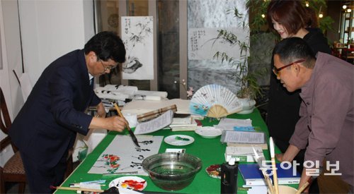 김남기 씨가 1일 전남 담양군 담양읍 한국대나무박물관갤러리에서 진행되는 기획초대전 ‘대숲에서 놀다’의 전시장 입구에서 배법연 씨 가족에게 서화 가훈을 써 주고 있다. 김 씨는 배 씨 가족들이 서화 가훈을 보고 즐거워하는 모습에 작은 행복을 느낀다고 했다. 이형주 기자 peneye09@donga.com