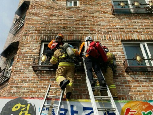 15일 충북 청주시 서원구 다세대주택 화재 현장에서 119구조대원들이 부상당한 여성을 아래로 옮기고 있다. 청주서부소방서 제공