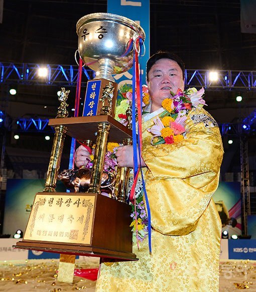 장성복(양평군청)이 21일 장충체육관에서 열린 ‘2016 천하장사 씨름대축제 ’ 천하장사 결정전에서 김재환(용인백옥쌀)을 3-0으로 꺾고 정상에 오른 뒤 우승트로피를 들고 환하게 웃고 있다. 장충 ｜ 김진환 기자 kwangshin00@donga.com