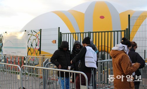 프랑스 파리 18구에 마련된 난민경유센터 앞에서 한 자원봉사자가 센터에 들어가지 못한 난민들에게 따뜻한 차를 건네고 있다.
 유럽 최대 규모로 지어졌지만 매일 150명 이상의 난민이 자리가 없어 발길을 돌리는 형편이다. 파리=동정민 특파원 
ditto@donga.com