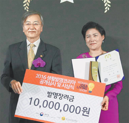 23일 ‘2016 생활발명코리아’ 시상식에서 북한 여군 장교 출신인 김정아 통일맘연합회 대표가 출품한 ‘속 시원한 세면기’로 대통령상(1등)과 상금 1000만
원을 받았다. 왼쪽은 최동규 특허청장. 특허청 제공