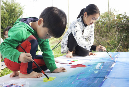 ‘어린이는 무엇을 믿는가’ 프로그램 중 ‘ㅇㅅㅇ사진과-엽서를 보내다’에 참석한 아이들이 무릎을 곧추세운 채 그림을 그리고 있다. 한국문화예술교육진흥원 제공