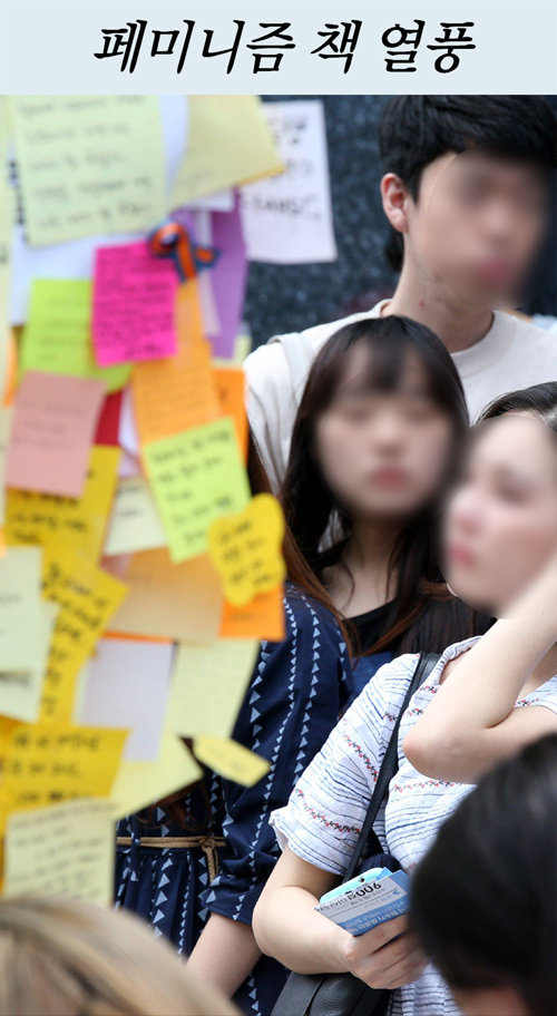 서울 강남역 인근에서 살해된 여성을 추모하는 글이 담긴 스티커 앞에 선 추모객들.