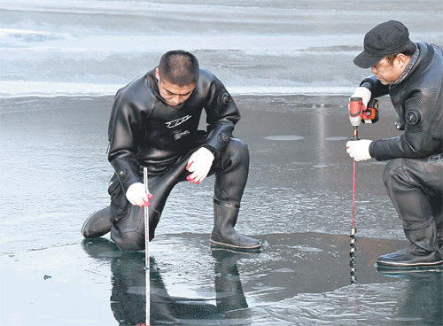 1일 강원 화천군 관계자들이 산천어축제가 열릴 화천천의 얼음 두께를 재고 있다. 이날 화천천의 얼음 두께는 10cm 정도였지만 2일 내린 비로 상당 부분 녹아 7일 개막이 어려워졌다. 화천군 제공