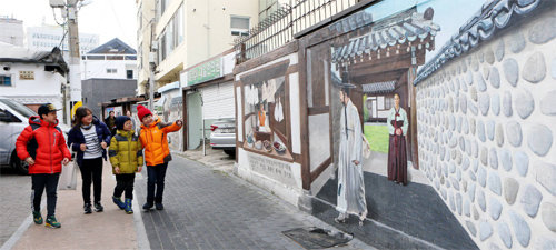 최근 대구 중구 영남대로를 찾은 어린이들이 조선시대 집을 나서는 선비와 배웅하는 부인의 모습을 나타낸 트릭아트(착시 그림)를 보며 걷고 있다. 대구 중구 제공