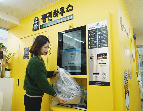 한 소비자가 서울 용산구 세븐일레븐 산천점에 설치된 무인 세탁 시스템에 빨랫감을 맡기고 있다. 세븐일레븐 제공