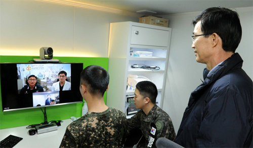 2월 27일 방문규 보건복지부 차관(오른쪽)이 방문한 경기 연천군 28사단 GOP 대대 의무실. 이곳에 설치된 원격진료 장비 부스에서 정영훈 상병(왼쪽)이 의무병의 도움을 받아 원격진료를 받고 있다. 보건복지부 제공