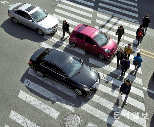 횡단보도를 침범한 차량들 사이로 보행자들이 위험하게 걸어가고 있다. 한국의 교통사고 사망자는 계속 줄고 있지만 보행자 사망 비율은 오히려 늘어나면서 보행 안전을 위한 시설과 제도 개선이 시급하다는 지적이 나온다. 동아일보DB