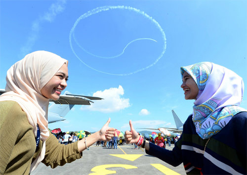 25일 말레이시아 랑카위에서 열린 방위산업전시회 ‘말레이시아 LIMA’ 관람객들이 한국 공군 특수비행팀 블랙이글스가 하늘에 수놓은 태극무늬를 보며 엄지를 세우고 있다. 공군 제공