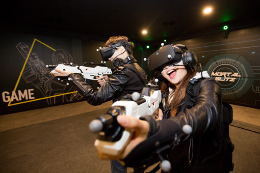 VR(가상현실) 공간에서 외계 괴생명체와 싸우는 슈팅게임 ‘서바이벌 모탈블리츠’를 즐기는 관람객들.