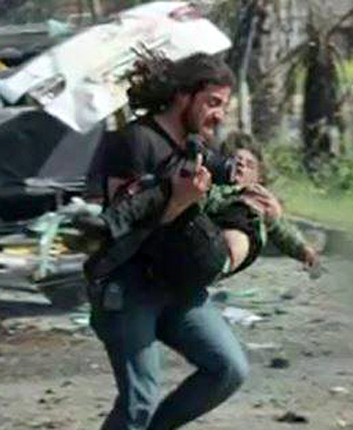 15일 시리아 알레포의 버스 테러 현장에서 사진작가인 아브드 알카데르 하바크 씨가 다친 어린이를 안고 뛰어가고 있다. CNN 홈페이지 캡처
