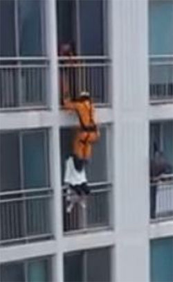 온라인에서 화제를 모은 일명 ‘자살 발차기’ 영상. 소방관이 아파트 위층 베란다에서 뛰어내리며 아래층 난간에 걸터앉아 있던 여성을 차서 집 안으로 밀어 넣고 있다. 유튜브 영상 캡처