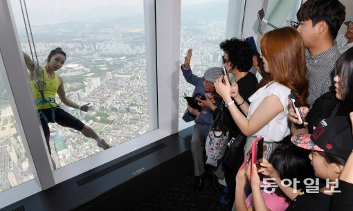 ‘클라이밍 여제’ 김자인이 20일 국내 최고층 건물인 서울 잠실 롯데월드타워(123층, 555m)를 맨손으로 오르자 실내에 있던 관람객들이 응원을 보내고 있다. 양회성 기자 yohan@donga.com